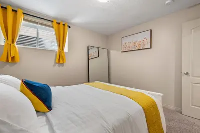 a bedroom with a bed and a window with yellow curtains at Panorama Hills Cozy Guest Suite in Calgary