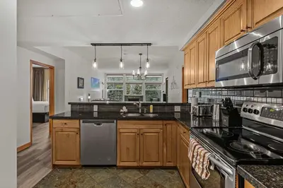 a kitchen with wooden cabinets and black counter tops at Tranquil Condo In The Trees Spacious 2Bd Hot Tub & Pool in Canmore