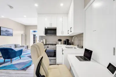 a kitchen with white cabinets and a laptop on a counter at 2 Bedroom Smart Secondary Suite with Gazebo view in Calgary