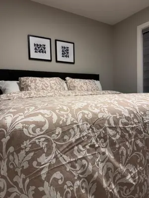 a bedroom with a bed with a comforter on it at NorthEdge Master Suite, Leduc in Leduc