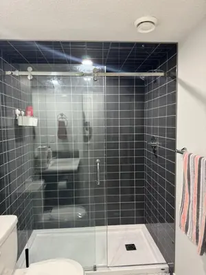 a bathroom with a glass shower with a toilet and a sink at Cozy 2 Bedroom Basement Apartment in Calgary