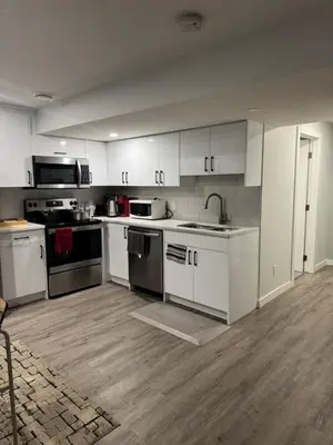 an empty kitchen with white cabinets and appliances at Cozy 2 Bedroom Basement Apartment in Calgary