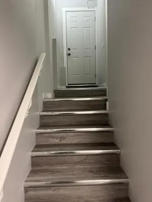 a hallway with stairs with a white door at Cozy 2 Bedroom Basement Apartment in Calgary