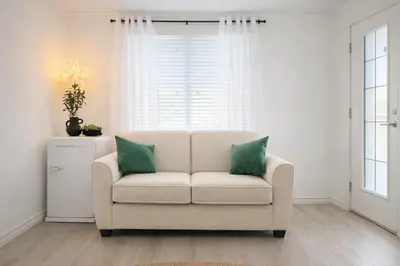 a living room with a white chair with two green pillows at Private Suite in Airdrie Near Calgary Free Parking in Airdrie
