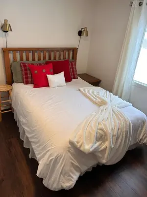 a bed with red pillows on it in a bedroom at Cozy Country Cabin in Lacombe