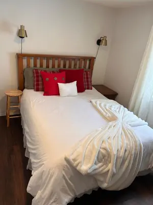 a bedroom with a white bed with red pillows at Cozy Country Cabin in Lacombe