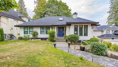 a white house with a blue door and a yard at Designer 2-Bedroom Garden-Level Walk-Out Suite in Surrey