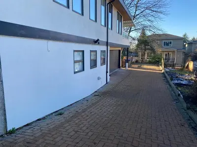 a brick sidewalk next to a white building at Designer 2-Bedroom Garden-Level Walk-Out Suite in Surrey