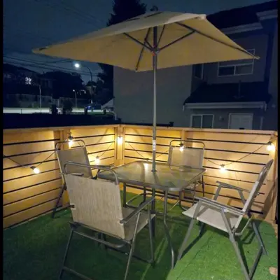 a table and chairs with an umbrella on a fence at Bohemian Theme Private Room near Metrotown Mall with private parking in Burnaby