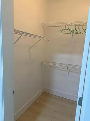 a walk in closet with white walls and wooden floors at Cozy Home in Surrey