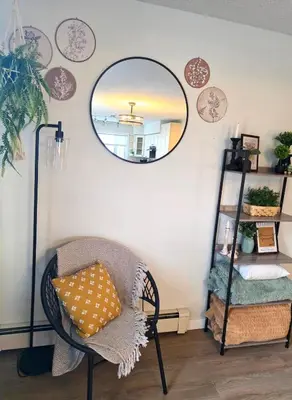 a room with a chair and a mirror on the wall at Small Town Pearl l Charming & Cozy 2 Level Suite Near Red Deer l Yard & BBQ in Penhold
