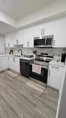 a kitchen with white cabinets and a black stove at 2BR 14minsYYC Airport Private Entrance Soft Water System in Calgary