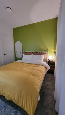 a bedroom with a large bed with a green wall at 2BR 14minsYYC Airport Private Entrance Soft Water System in Calgary