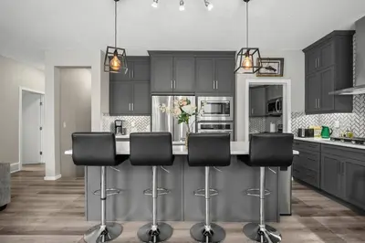 a kitchen with black cabinets and black bar stools at Bright & Spacious Family Retreat in Calgary