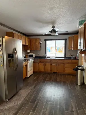 a kitchen with wooden cabinets and a stainless steel refrigerator at Cowboy Cabin- Lakefront Rental Northern Saskatchewan