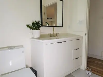 a white bathroom with a sink and a mirror at 2 bedroom suite close to Main and Skytrain in Vancouver
