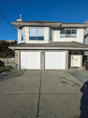 a white house with two white garage doors at 2 bedroom suite close to Main and Skytrain in Vancouver