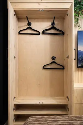 a bedroom with hangers in a wooden wall at The Bear Cave - Artist-Inspired Suite in Langford