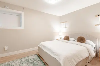 a white bedroom with a bed and a window at Modern Bright Suite Self Check-In in North Vancouver