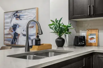 a kitchen counter with a sink and a vase with a plant at Herron Rise Luxury 1 Bedroom Basement Suite in Calgary
