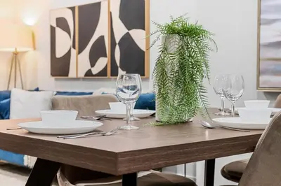 a wooden table with plates and wine glasses on it at Herron Rise Luxury 1 Bedroom Basement Suite in Calgary