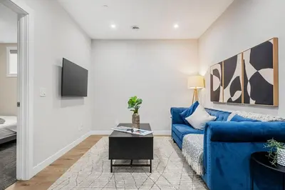a living room with a blue couch and a tv at Herron Rise Luxury 1 Bedroom Basement Suite in Calgary