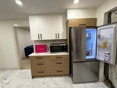 an empty kitchen with a refrigerator and a microwave at Vancouver Downtown Cozy Room - 5-Min Walk to BC Place & Skytrain - Free Parking in Vancouver