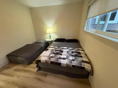 two beds in a small room with a window at Vancouver Downtown Cozy Room - 5-Min Walk to BC Place & Skytrain - Free Parking in Vancouver