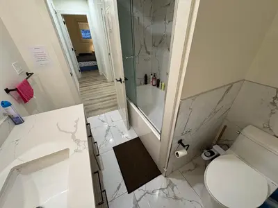a white bathroom with a shower and a toilet at Vancouver Downtown Cozy Room - 5-Min Walk to BC Place & Skytrain - Free Parking in Vancouver