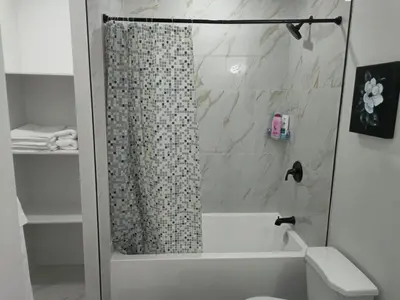 a bathroom with a shower curtain and a toilet at Mayfair Suite in Airdrie