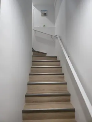 a stairway with white walls and wooden stairs at Mayfair Suite in Airdrie