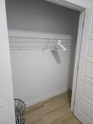 a closet with a shelf and a door with a chair at Mayfair Suite in Airdrie