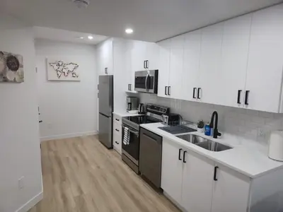 a kitchen with white cabinets and stainless steel appliances at Mayfair Suite in Airdrie