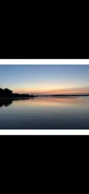 a framed picture of a lake at sunset at Spacious 4-Season Cabin with Lakefront Views in Silver Sands in Seba Beach