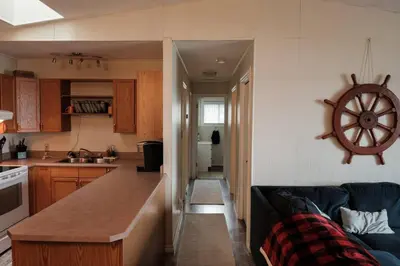 a kitchen and a living room with a blue couch at Spacious 4-Season Cabin with Lakefront Views in Silver Sands in Seba Beach