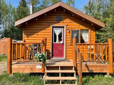 a cabin with a red door on a wooden deck at The Mustang Cabin - Bear Creek Cabins in Winfield