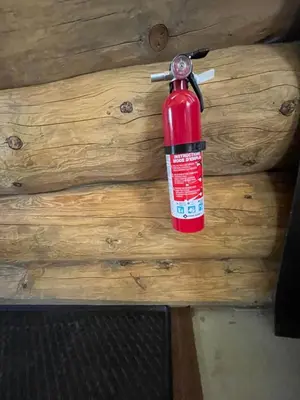 a red fire extinguisher hanging on a wooden wall at The Ram cabin - Bear Creek cabins in Winfield