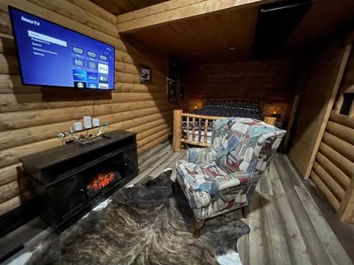 a living room with a fireplace and a tv at The Lynx cabin - Bear Creek Cabins in Winfield