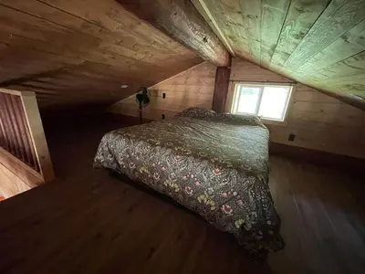 a bed in a wooden room with a window at The Deerview cabin - a part of Bear Creek Cabins in Winfield
