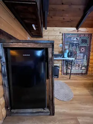a large black tv in a room with wooden walls at The Sheep Camp cabin- Bear Creek Cabins in Winfield