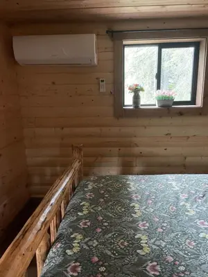 a bed in a log cabin with a window at The Cowboy cabin - Bear Creek Cabins in Winfield