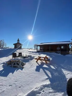 a snow covered area with a building with the sun behind it at The Moose cabin - Bear Creek Cabins in Winfield