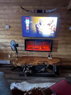 a living room with a fireplace and a tv at The Longhorn cabin - Bear Creek Cabins in Winfield