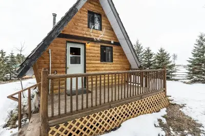 a log cabin with a porch in the snow at The Papa Bear Cabin - Bear Creek Cabins in Winfield