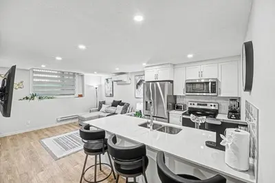 a kitchen with a counter and a kitchen island with chairs at Stylish 2BR Townhome - Near YYC Airport - Free Parking in Calgary