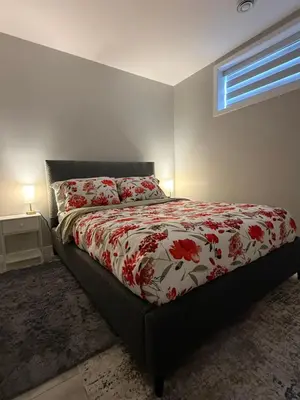 a bedroom with a bed with a red and white comforter at Slice Of Paradise in Calgary