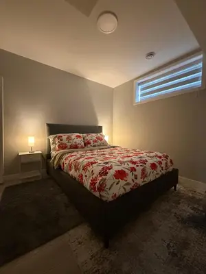 a bedroom with a bed with a red comforter and a window at Slice Of Paradise in Calgary