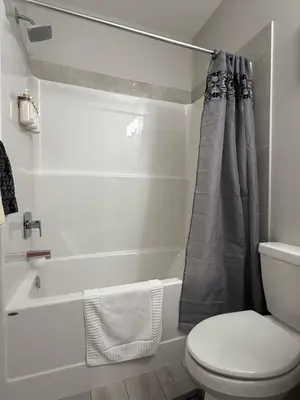 a white bathroom with a toilet and a bath tub at Slice Of Paradise in Calgary
