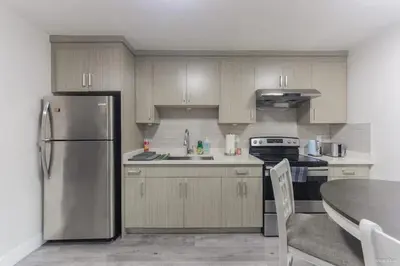 a kitchen with wooden cabinets and a stainless steel refrigerator at The Cozy Garden Suite - South Surrey Stay in White Rock