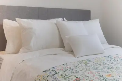 a bed with white pillows and a bunch of pillows at The Cozy Garden Suite - South Surrey Stay in White Rock